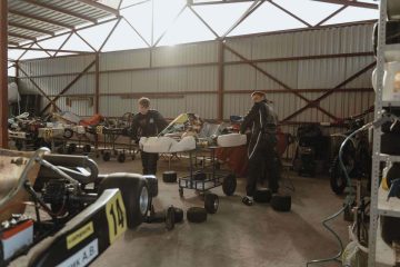 Deux personnes travaillent sur des kartings dans un entrepôt