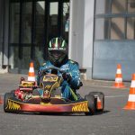 Un homme en karting, avec des cônes de signalisation orange et blanche