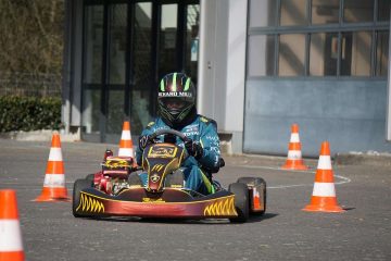 Un homme en karting, avec des cônes de signalisation orange et blanche